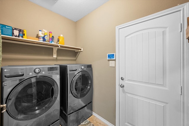 clothes washing area with a textured ceiling, laundry area, baseboards, tile patterned floors, and washer and clothes dryer