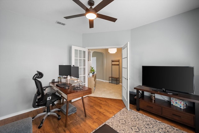 office area featuring arched walkways, french doors, visible vents, a ceiling fan, and wood finished floors