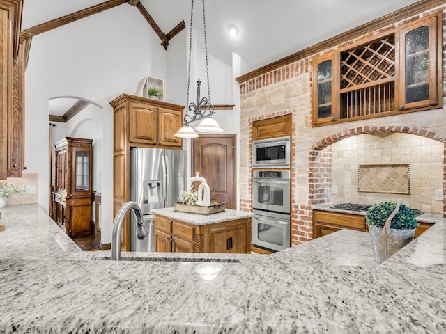 1300 Ruby Lea Ln, Fort Worth, TX 76179 - kitchen featuring appliances with stainless steel finishes, light stone counters, glass insert cabinets, brown cabinetry, and decorative light fixtures