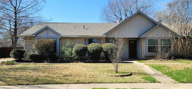 view of front of home with a chimney, a front lawn, and brick siding