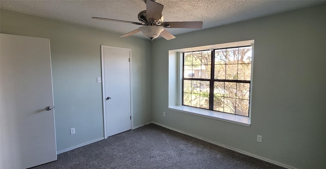 unfurnished bedroom with ceiling fan, dark carpet, and a textured ceiling