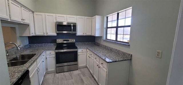 kitchen featuring appliances with stainless steel finishes, a sink, white cabinetry, and light stone countertops