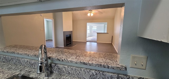 kitchen with a fireplace, lofted ceiling, ceiling fan, wood finished floors, and baseboards