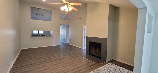 unfurnished living room featuring visible vents, dark wood finished floors, ceiling fan, a fireplace, and high vaulted ceiling