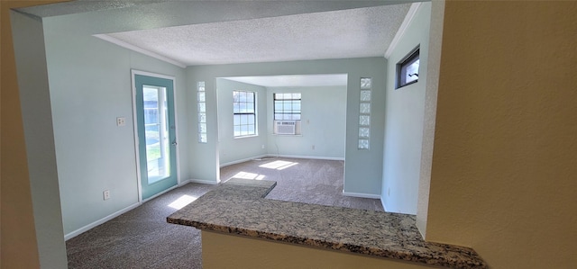 carpeted foyer entrance featuring a textured ceiling, baseboards, and crown molding