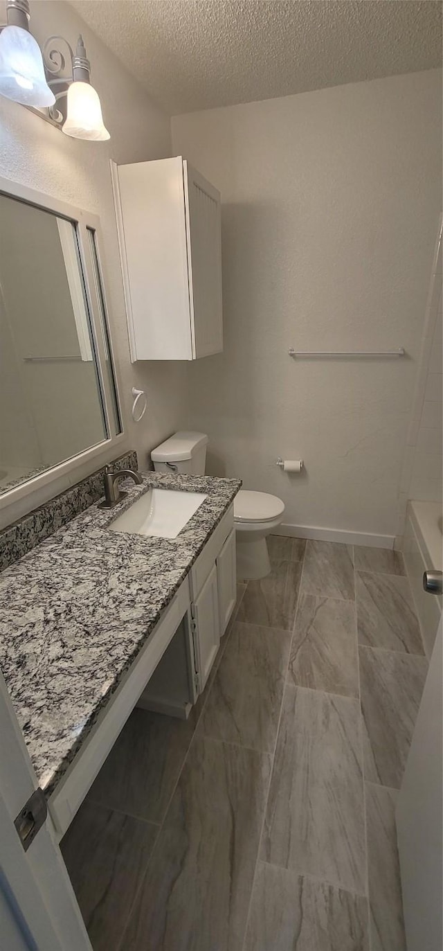 bathroom with toilet, baseboards, a textured ceiling, and vanity