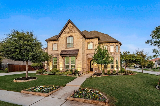 french country home with a front yard, fence, and brick siding