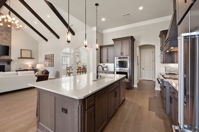 kitchen featuring arched walkways, a sink, open floor plan, light countertops, and hanging light fixtures