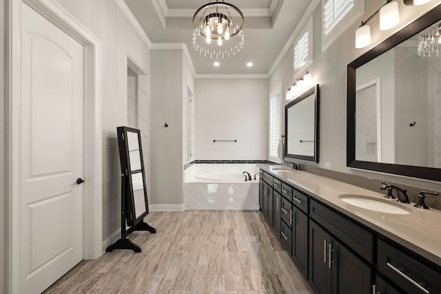 bathroom with a garden tub, an inviting chandelier, a sink, and crown molding