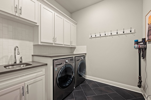 clothes washing area featuring cabinet space, a sink, dark tile patterned flooring, independent washer and dryer, and baseboards