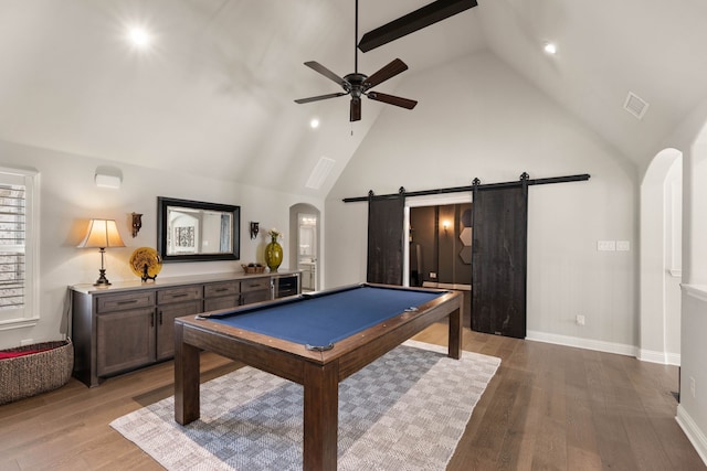 recreation room featuring arched walkways, light wood finished floors, visible vents, a barn door, and high vaulted ceiling