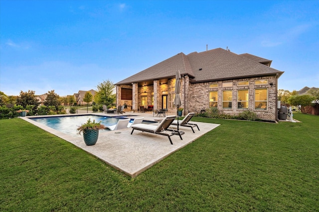 rear view of house with a yard, a patio area, an outdoor pool, and brick siding