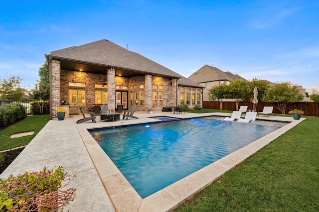 view of swimming pool featuring a yard, a patio area, and a fenced backyard