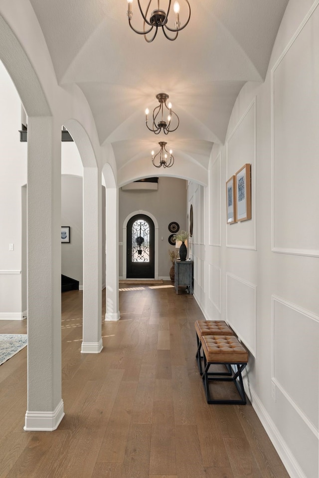 hall with arched walkways, wood finished floors, lofted ceiling, and baseboards