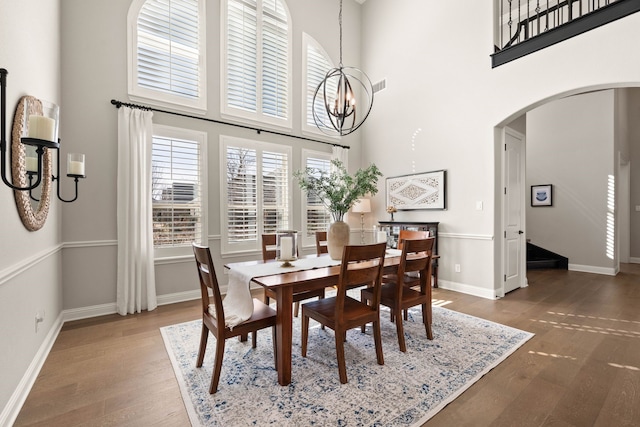 dining area featuring baseboards, arched walkways, dark wood finished floors, and a notable chandelier