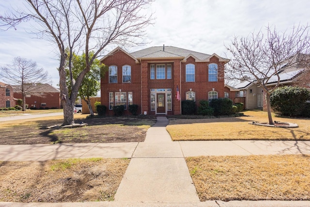 view of front of house with brick siding and a front lawn