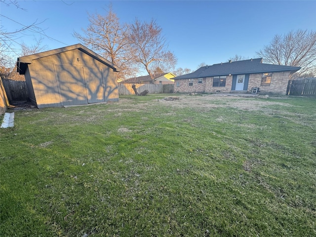 view of yard with a fenced backyard, an outdoor structure, and a storage unit