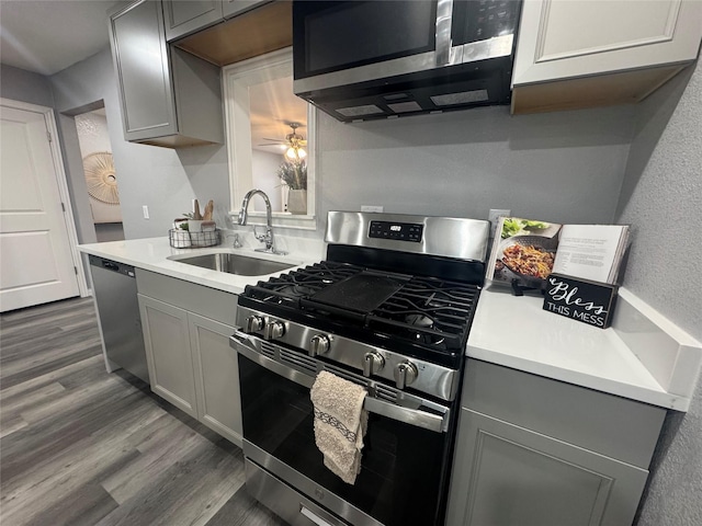 kitchen with dark wood-style floors, stainless steel appliances, light countertops, gray cabinetry, and a sink