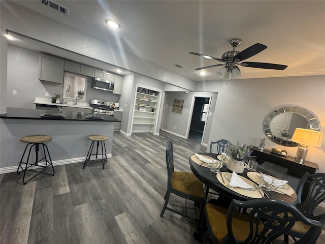 dining area with dark wood-style floors, baseboards, visible vents, and ceiling fan