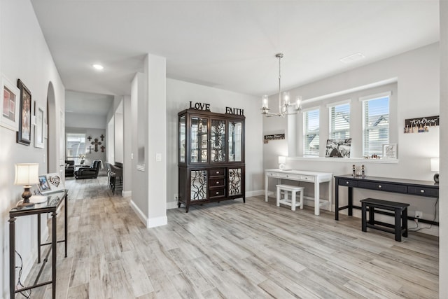 dining space featuring arched walkways, recessed lighting, a notable chandelier, baseboards, and light wood-type flooring