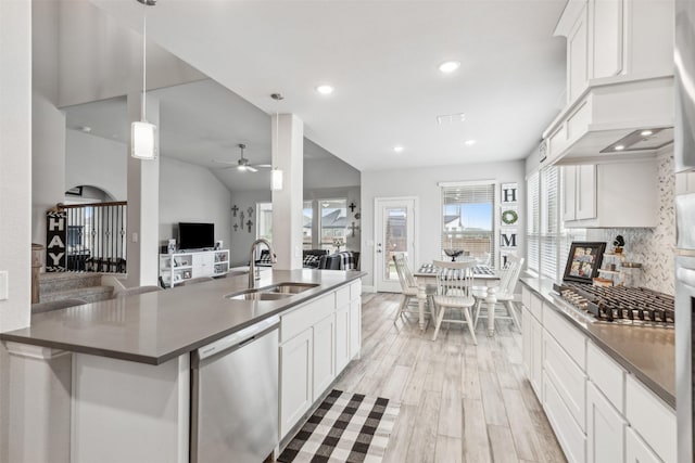 kitchen featuring dark countertops, appliances with stainless steel finishes, open floor plan, white cabinetry, and a sink