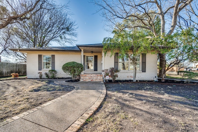 ranch-style home featuring brick siding and fence