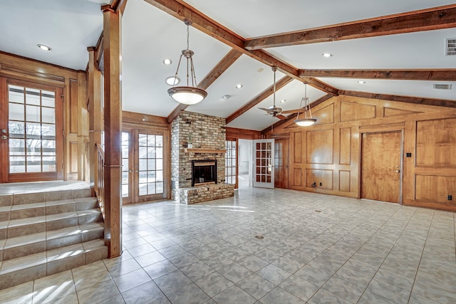 unfurnished living room with a brick fireplace, visible vents, vaulted ceiling with beams, and wooden walls