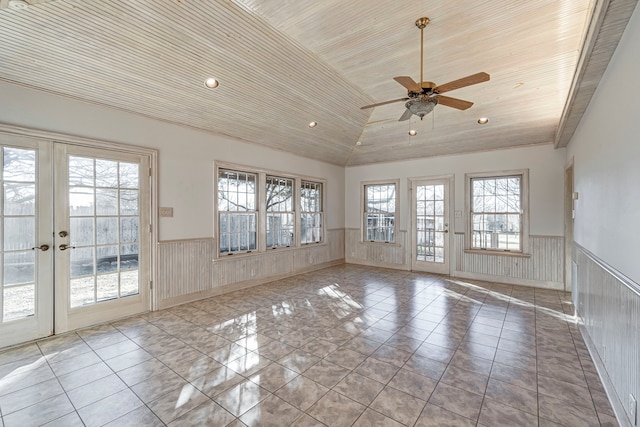 empty room with a wainscoted wall, french doors, lofted ceiling, and wood ceiling