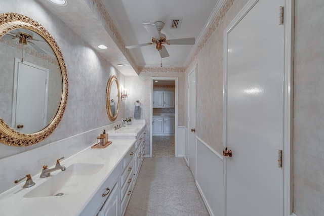 full bath featuring crown molding, double vanity, visible vents, a sink, and wallpapered walls