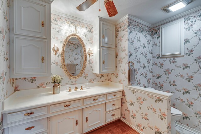529 N Grand Ave, Waxahachie, TX 75165 - bathroom featuring vanity, wood finished floors, toilet, a ceiling fan, and wallpapered walls
