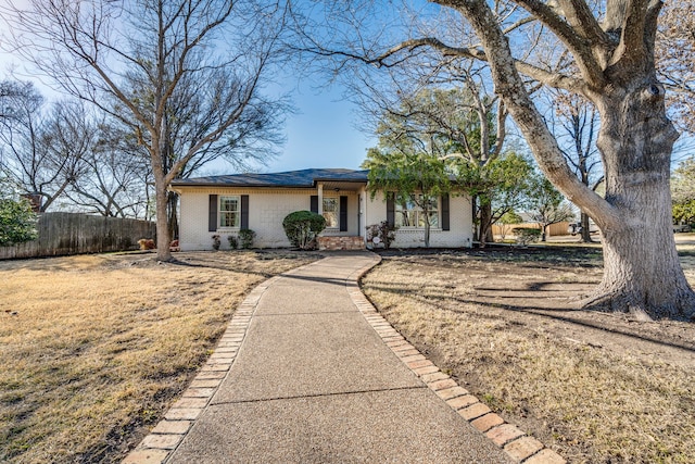 ranch-style home featuring brick siding, a front lawn, and fence