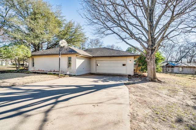 exterior space featuring an attached garage, brick siding, fence, driveway, and a chimney