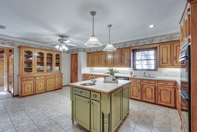 kitchen with decorative light fixtures, a center island with sink, light countertops, green cabinets, and a sink