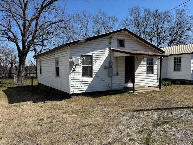 view of front of house featuring entry steps, fence, and a front lawn