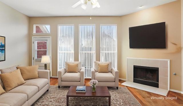 living room with a ceiling fan, wood finished floors, a fireplace, and baseboards