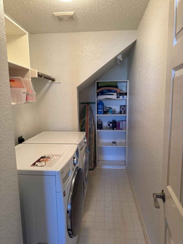 washroom featuring baseboards, visible vents, laundry area, a textured ceiling, and washer and clothes dryer