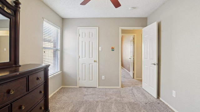 carpeted bedroom featuring multiple windows, a textured ceiling, a ceiling fan, and baseboards