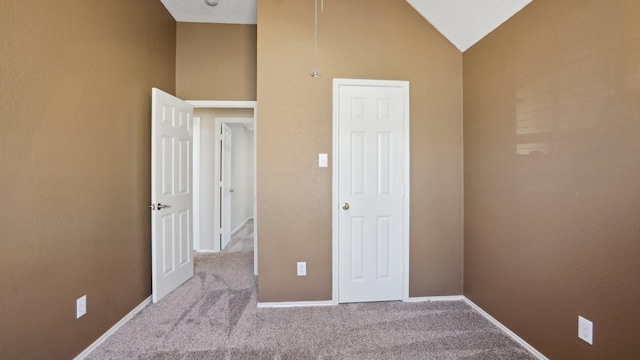 unfurnished bedroom featuring carpet floors, baseboards, and vaulted ceiling