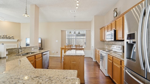 kitchen with a sink, backsplash, a center island, appliances with stainless steel finishes, and dark wood-style flooring