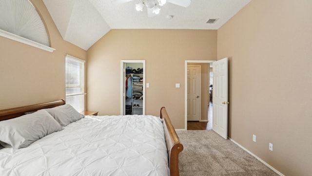 bedroom with visible vents, a walk in closet, baseboards, carpet flooring, and lofted ceiling