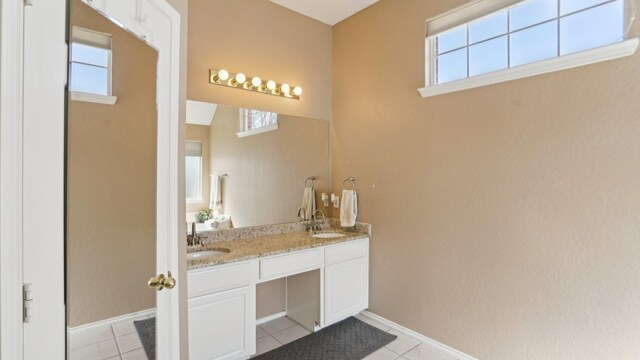 bathroom with tile patterned floors, a healthy amount of sunlight, and a sink