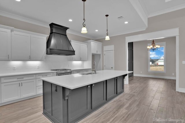 kitchen featuring light countertops, premium range hood, a sink, and white cabinets