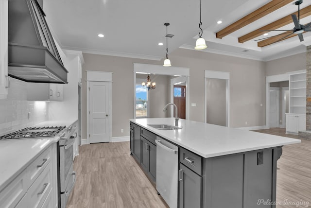 kitchen with stainless steel appliances, a sink, hanging light fixtures, light countertops, and an island with sink