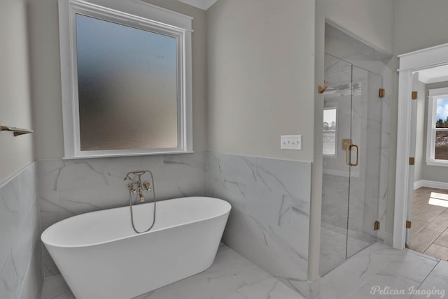 full bathroom featuring marble finish floor, a wainscoted wall, a soaking tub, and a marble finish shower