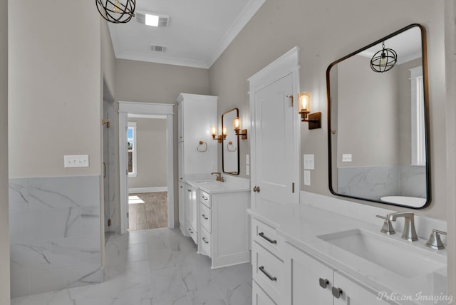 bathroom featuring marble finish floor, ornamental molding, a sink, and visible vents