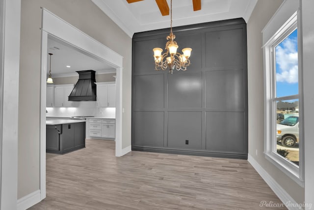 unfurnished dining area with a notable chandelier, light wood-style floors, ornamental molding, and a decorative wall