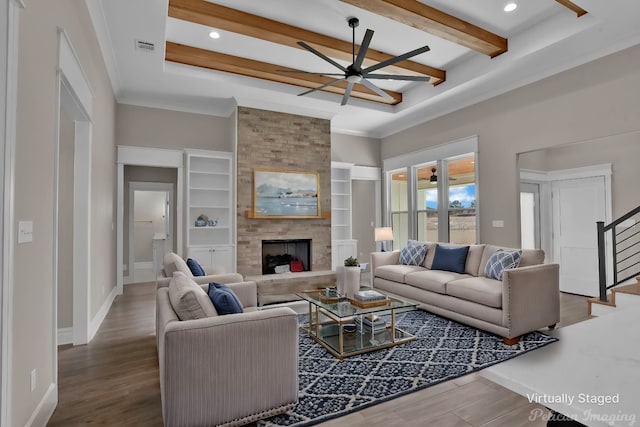 living area with beam ceiling, stairway, a large fireplace, wood finished floors, and baseboards