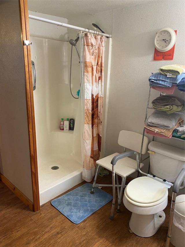 bathroom featuring wood finished floors, a shower stall, and toilet