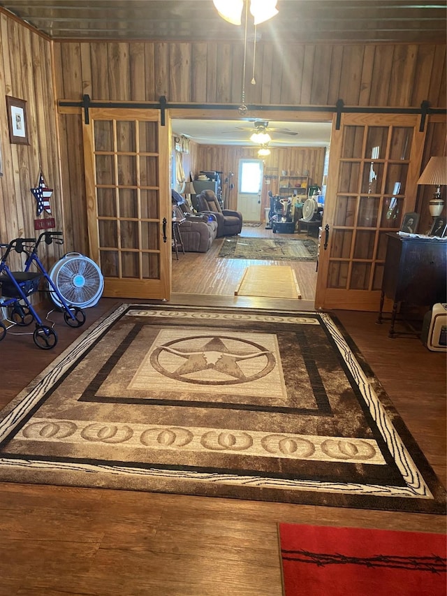 hall with a barn door, wood walls, and wood finished floors