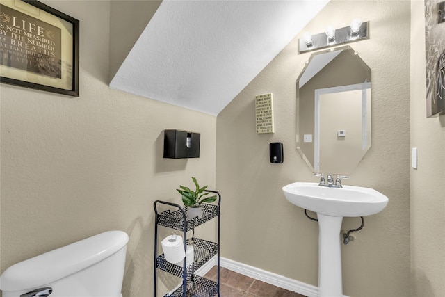 bathroom featuring a textured wall, toilet, and baseboards